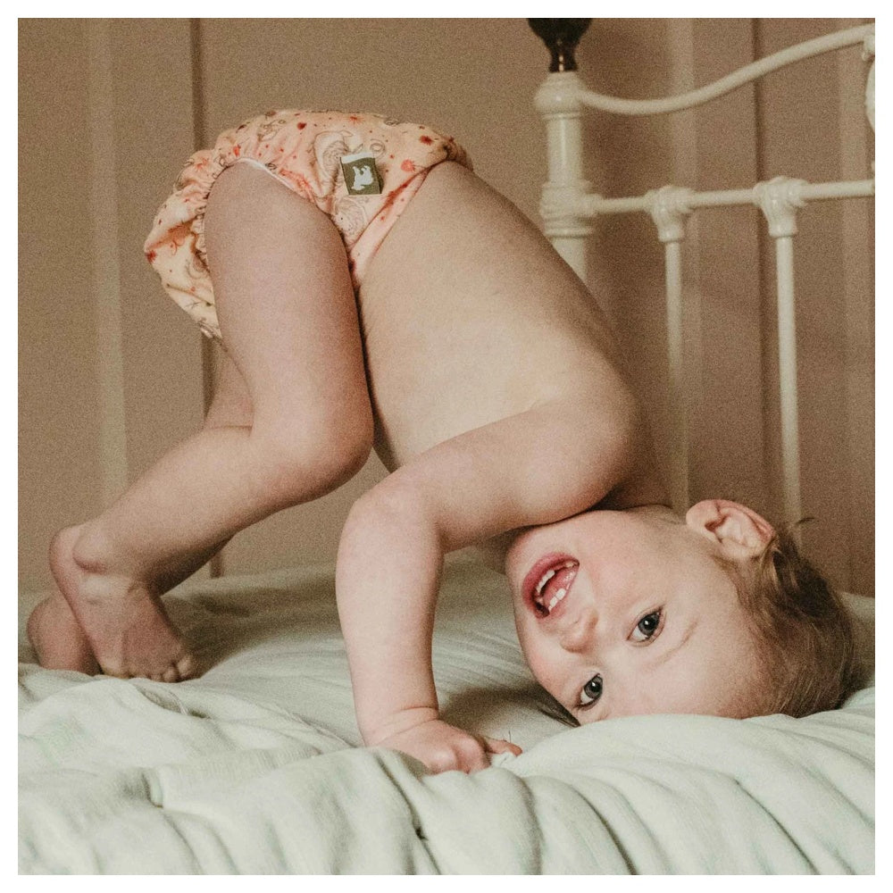 Lachendes Baby liegt auf dem Bett und trägt eine Little Lamb Pocketwindel, Anwendungsbeispiel