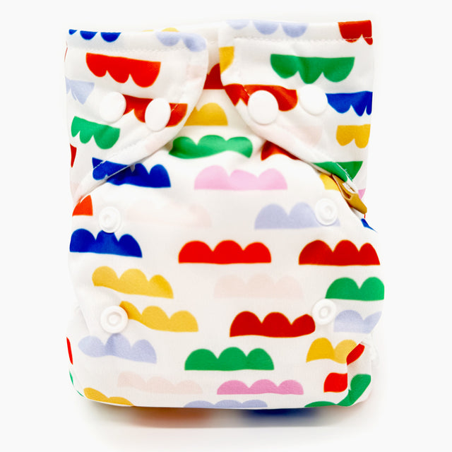 Little Clouds Prefold-Überhose Gold Edition im Design Clouds schräg von vorn: bunte Wolkenmotive auf weißem Grund
