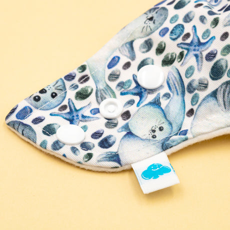 Nahaufnahme der Little Clouds Prefold-Überhose aus PUL im Design Robben mit Druckknöpfen und blauem Little-Clouds-Etikett