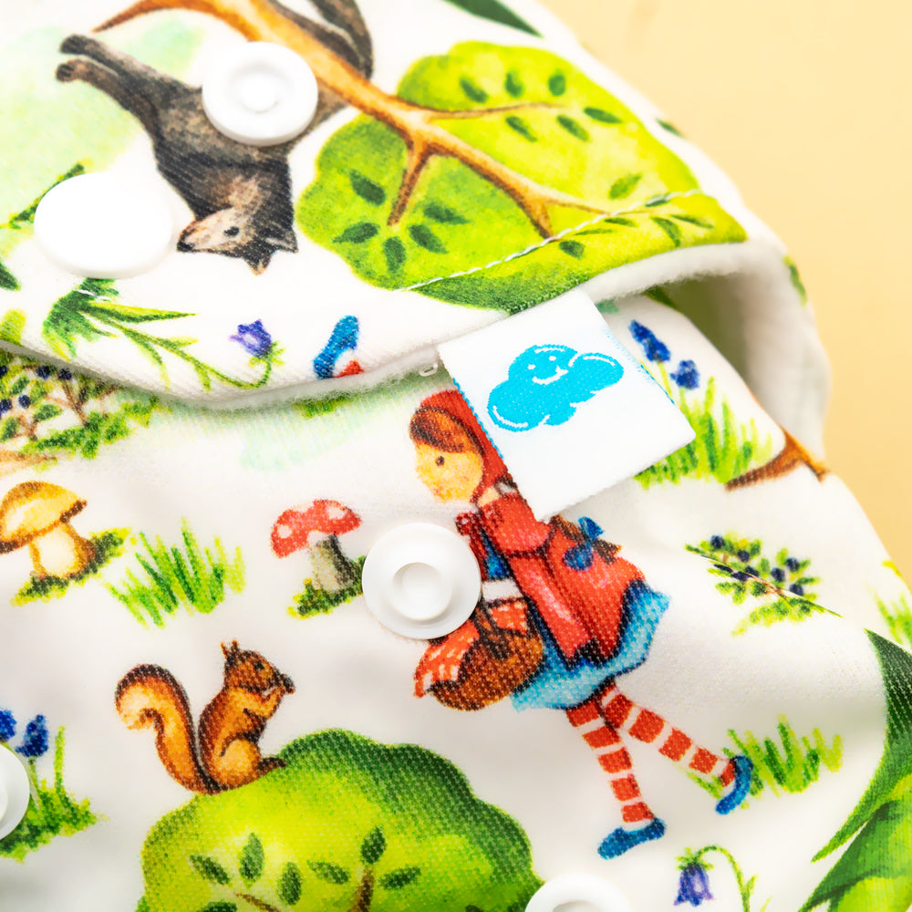 Nahaufnahme der Little Clouds Prefold-Überhose aus PUL im Design Rotkäppchen mit Druckknöpfen und Märchenfiguren wie Eichhörnchen und Wolf