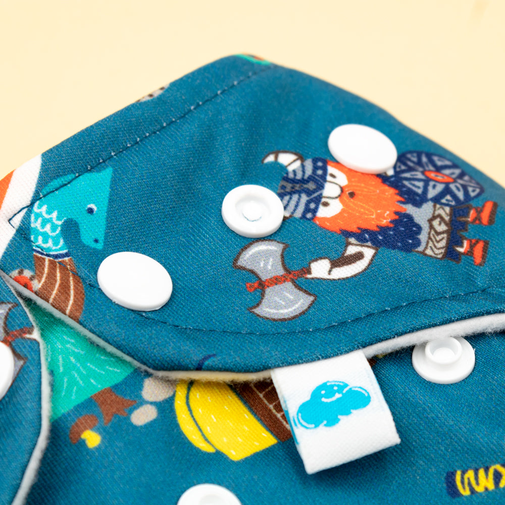 Nahaufnahme der Little Clouds Prefold-Überhose aus PUL im Design Wikinger mit Druckknöpfen und blauem Etikett