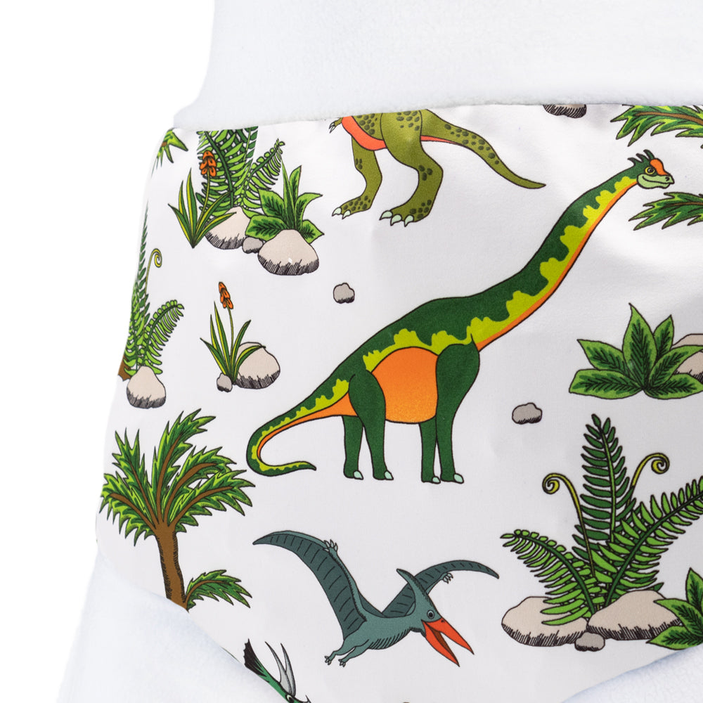 Nahaufnahme der Little Clouds Schlupfhose V2 aus PUL im Design Dino World: Dinosaurier und Palmen auf hellem Grund