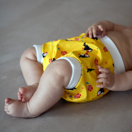 Baby liegt auf dem Rücken und trägt eine Little Clouds Schlupfhose aus PUL – Anwendungsbeispiel im Design Papageientaucher