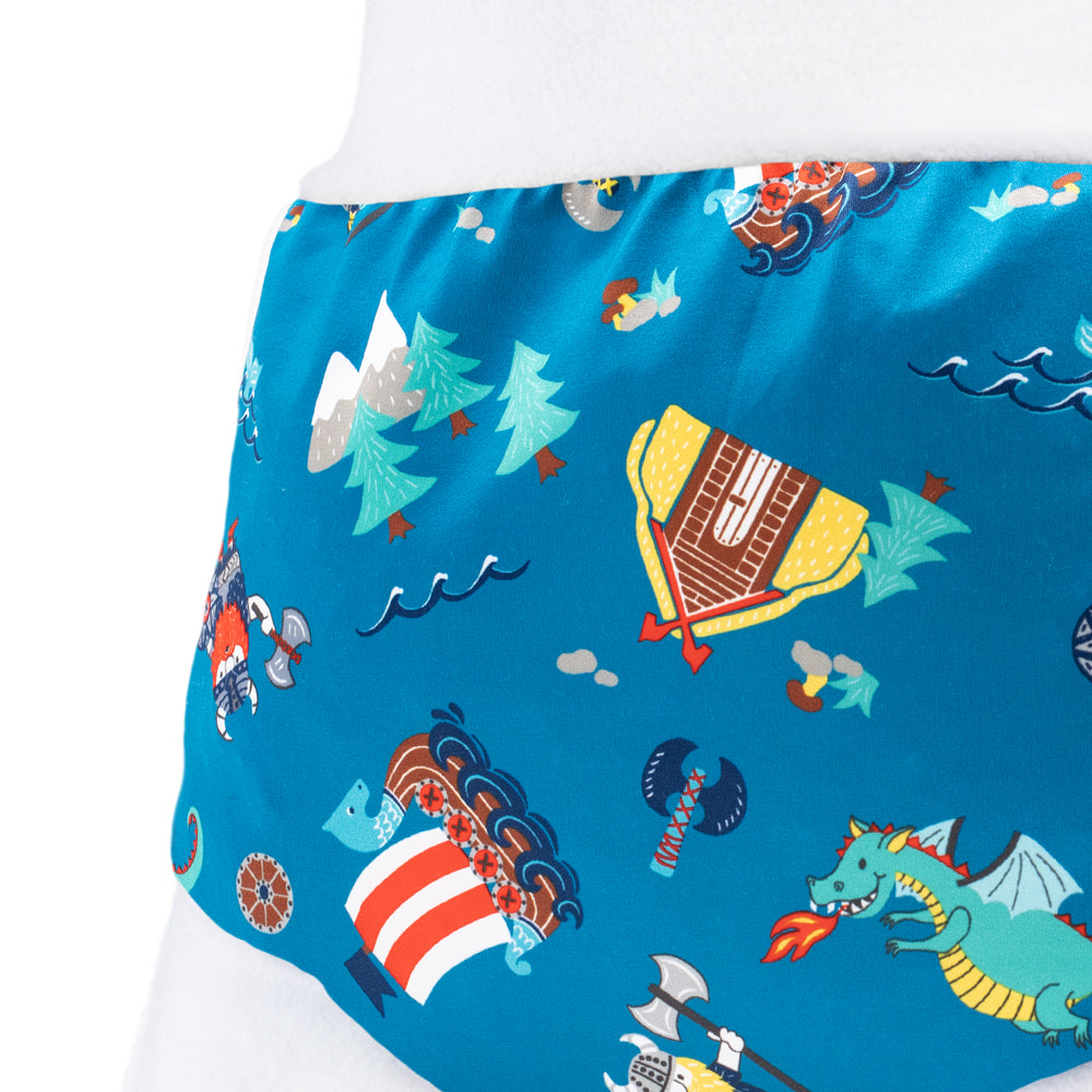 Nahaufnahme der Little Clouds Schlupfhose V2 aus PUL im Design Wikinger: Wikingerschiffe und Zelte auf petrolblauem Grund