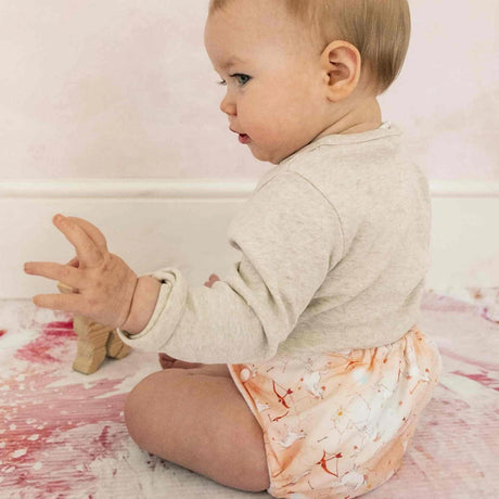 Sitzendes Baby trägt die Little Lamb Pocketwindel im Design Sagittarius (Schütze)
