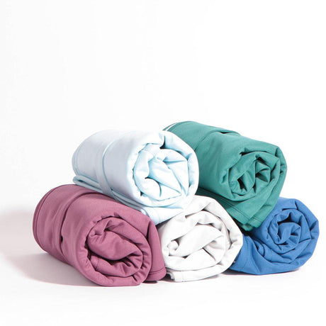Fünf aufgerollte Little Lamb Magic Foldaway Wickelunterlagen in Aubergine, Weiß, Grün, Blau und Hellblau